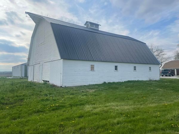 Crew installing metal roof panels on 100-year-old barn — in progress
