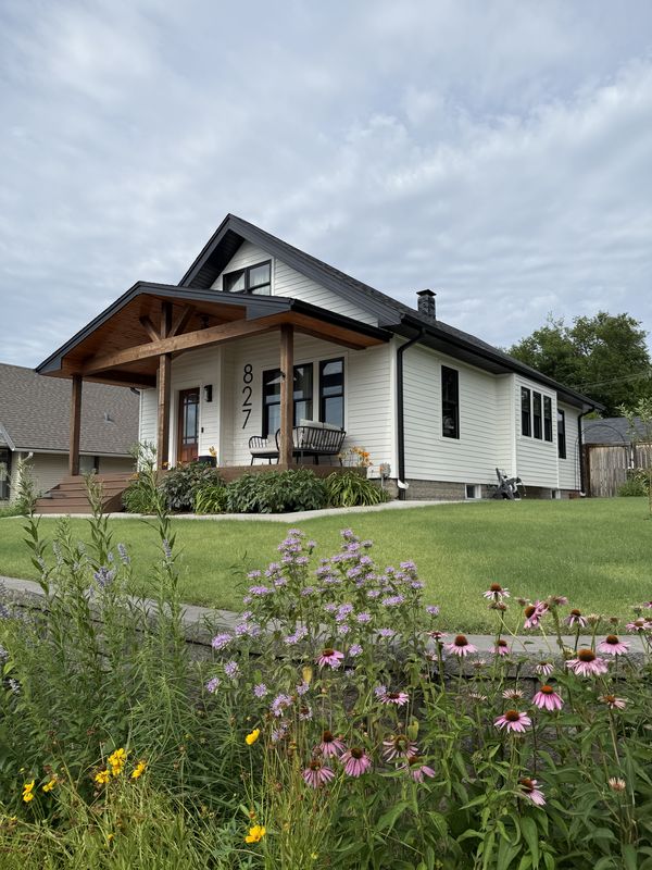 White farmhouse with new lap siding, black-frame windows, new roof, and timber porch