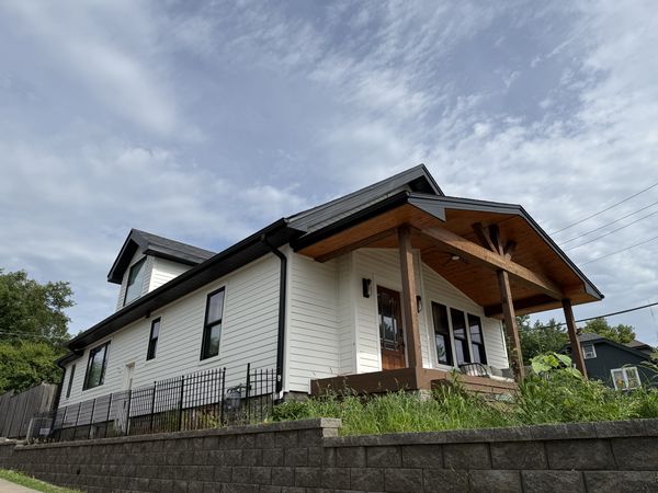 Side view of farmhouse showing new siding, new roof, and timber porch